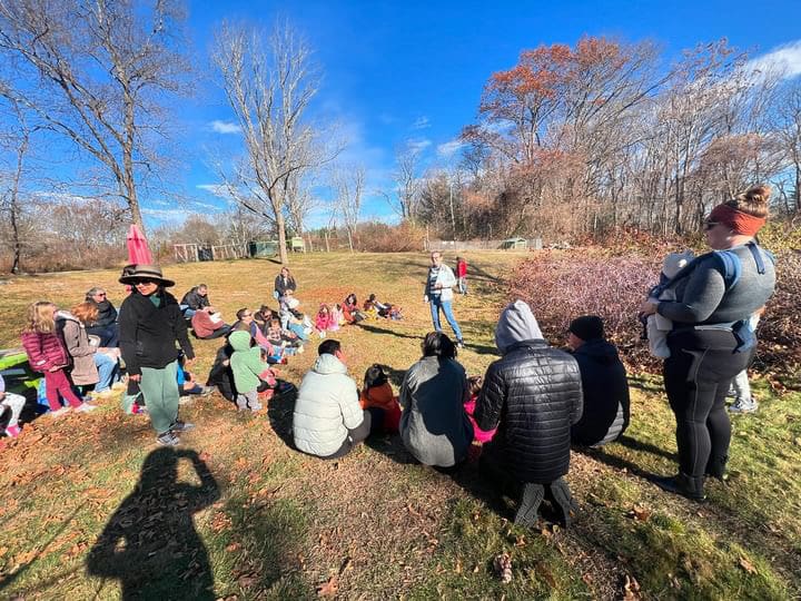 Group of people sitting outdoors on grass.