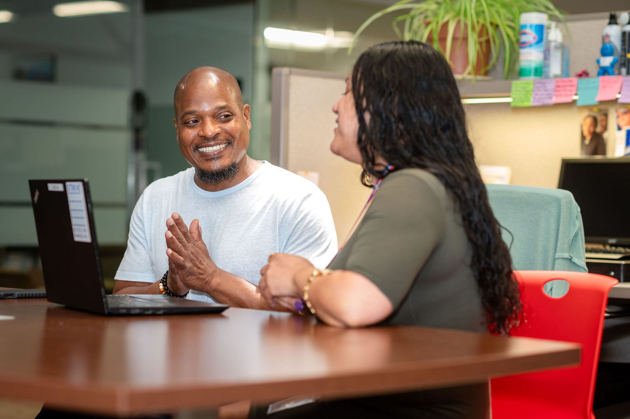 Two people talking at a desk with a laptop