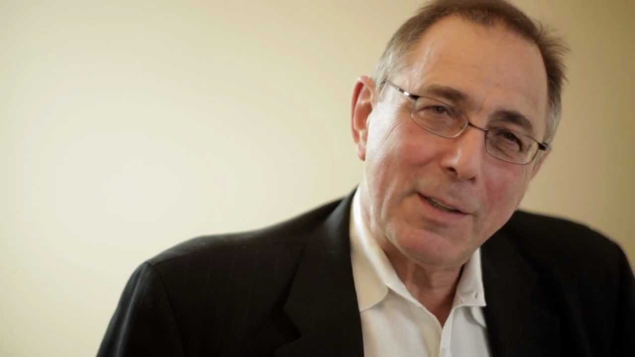 Person in glasses and a suit jacket smiling slightly at the camera.
