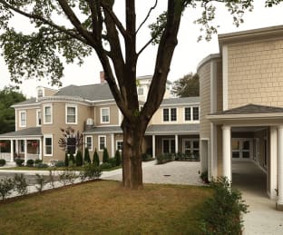 Residential building with large trees and landscaping