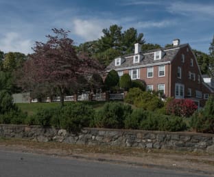 Large brick building with trees and shrubs in front.