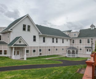 Large gray building with white trim and a rounded driveway