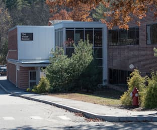 Exterior of a building with trees and a fire hydrant nearby.