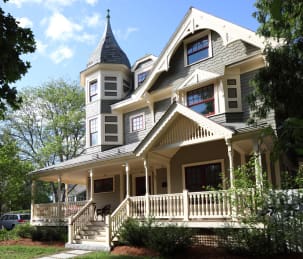 A large historic house with a wraparound porch and turrets.