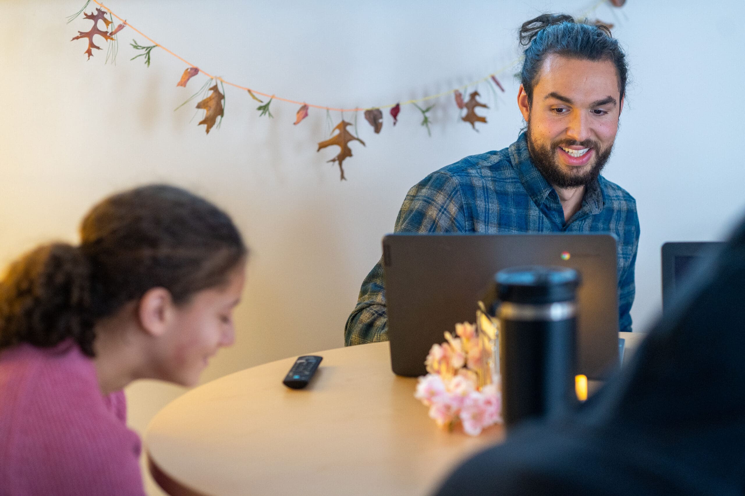 Two people laughing at a table in a room decorated with autumn leaves.