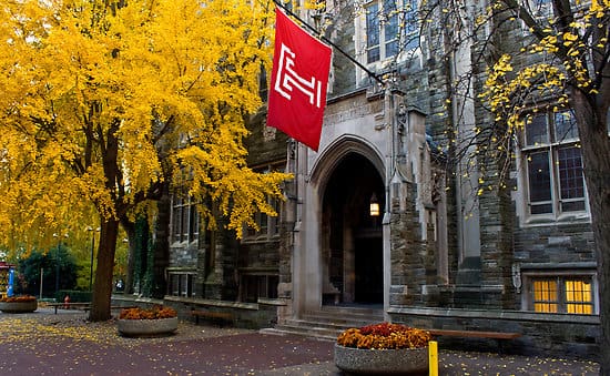 Temple University building entrance with red flag and yellow trees
