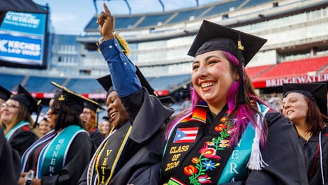Graduates in caps and gowns celebrating outdoor ceremony.