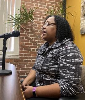 Person speaking into a microphone during an event.