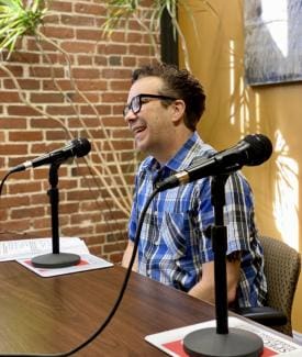 Person speaking into microphone at a table.