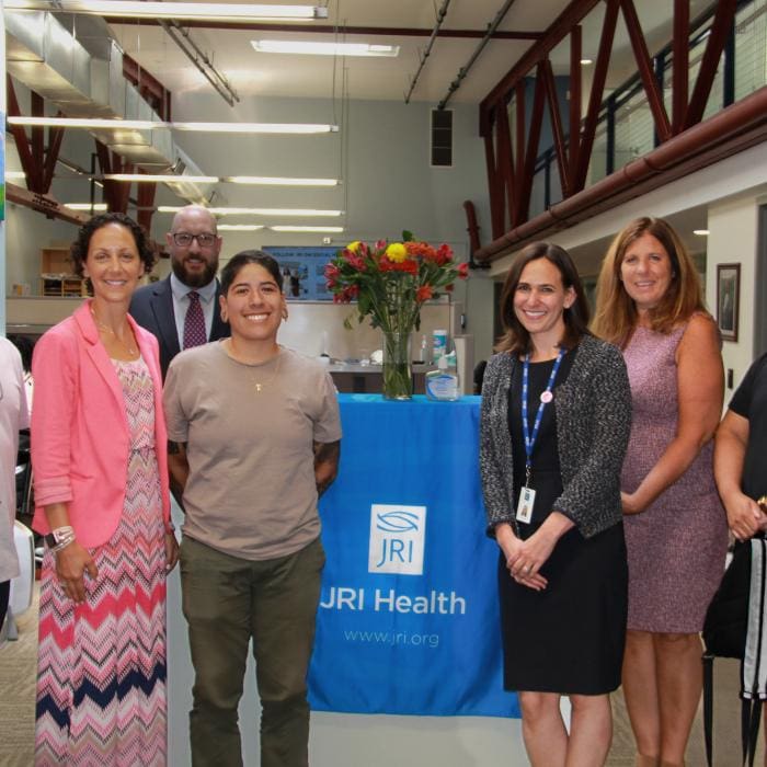 Group of five people smiling, standing next to a JRI Health banner.