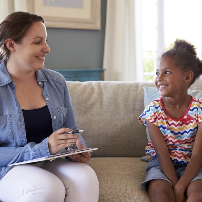 Woman and girl smiling at each other on a sofa.