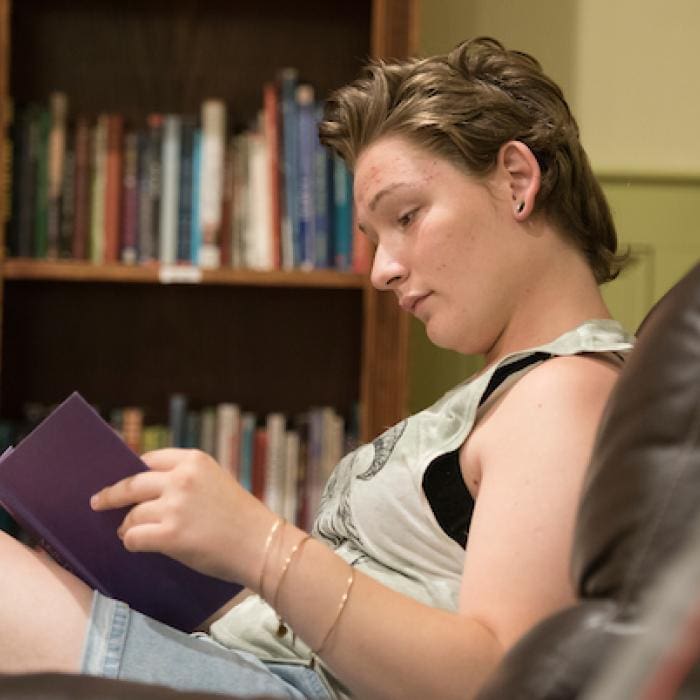 Student reading a book in a library.