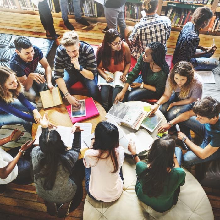 Group of young people sitting and talking in a library.