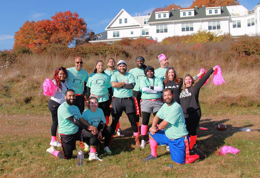Group of people in football uniforms and cheerleading accessories outdoors.