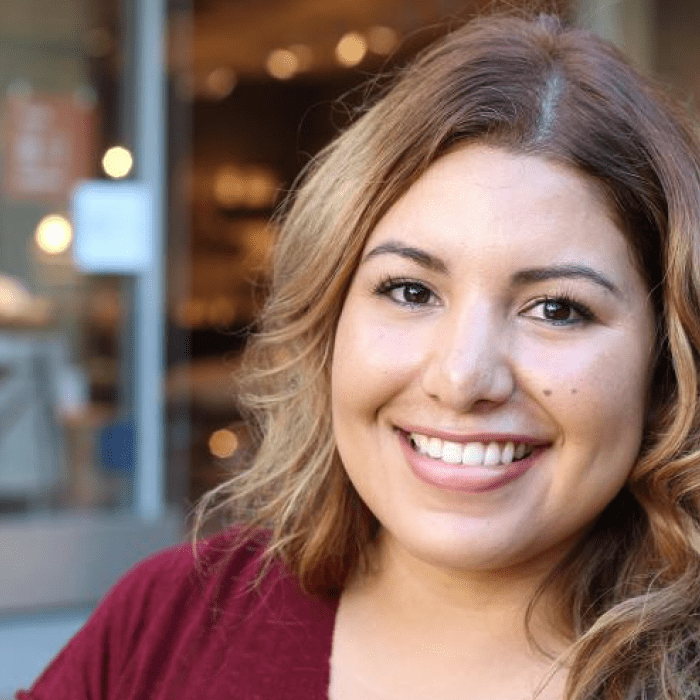 Young adult with shoulder-length light brown hair and a warm smile.