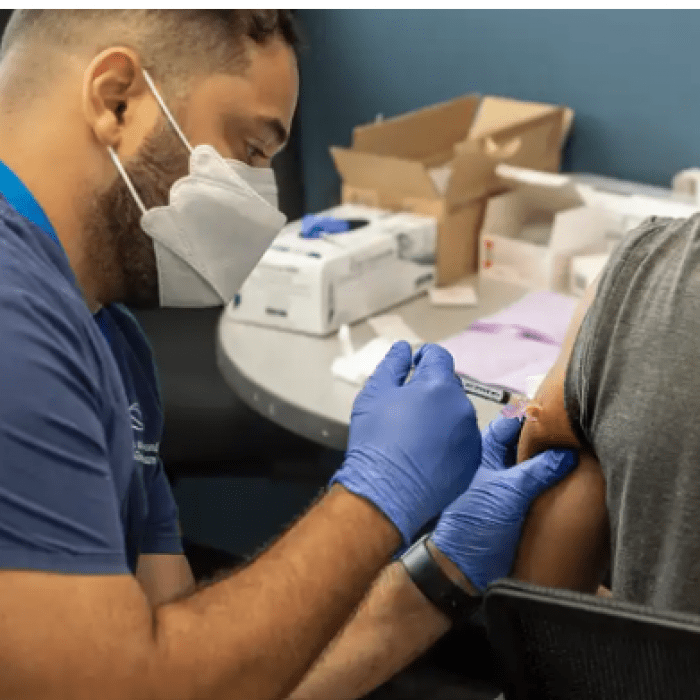 Health worker in mask and gloves administering vaccine to person