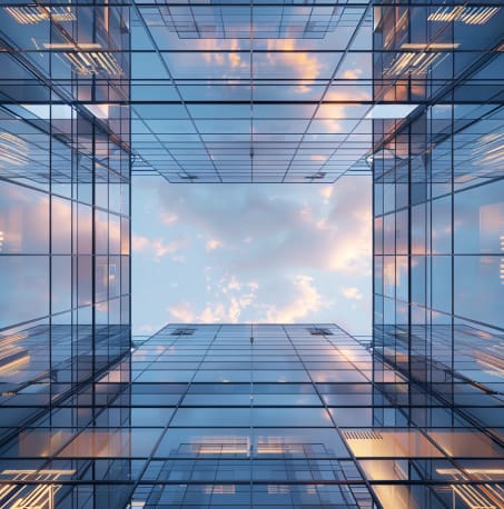 Looking up at a glass building's interior courtyard with sky visible above