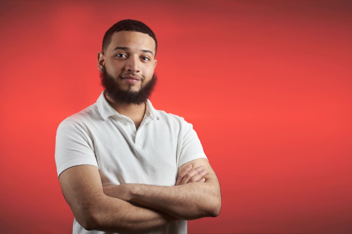 Young man with beard and crossed arms wearing a white shirt.