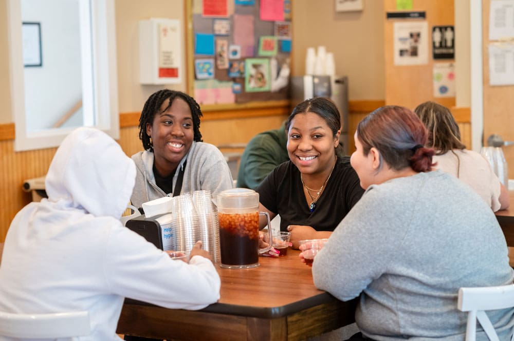 Group of five people sitting around a table, smiling and talking.
