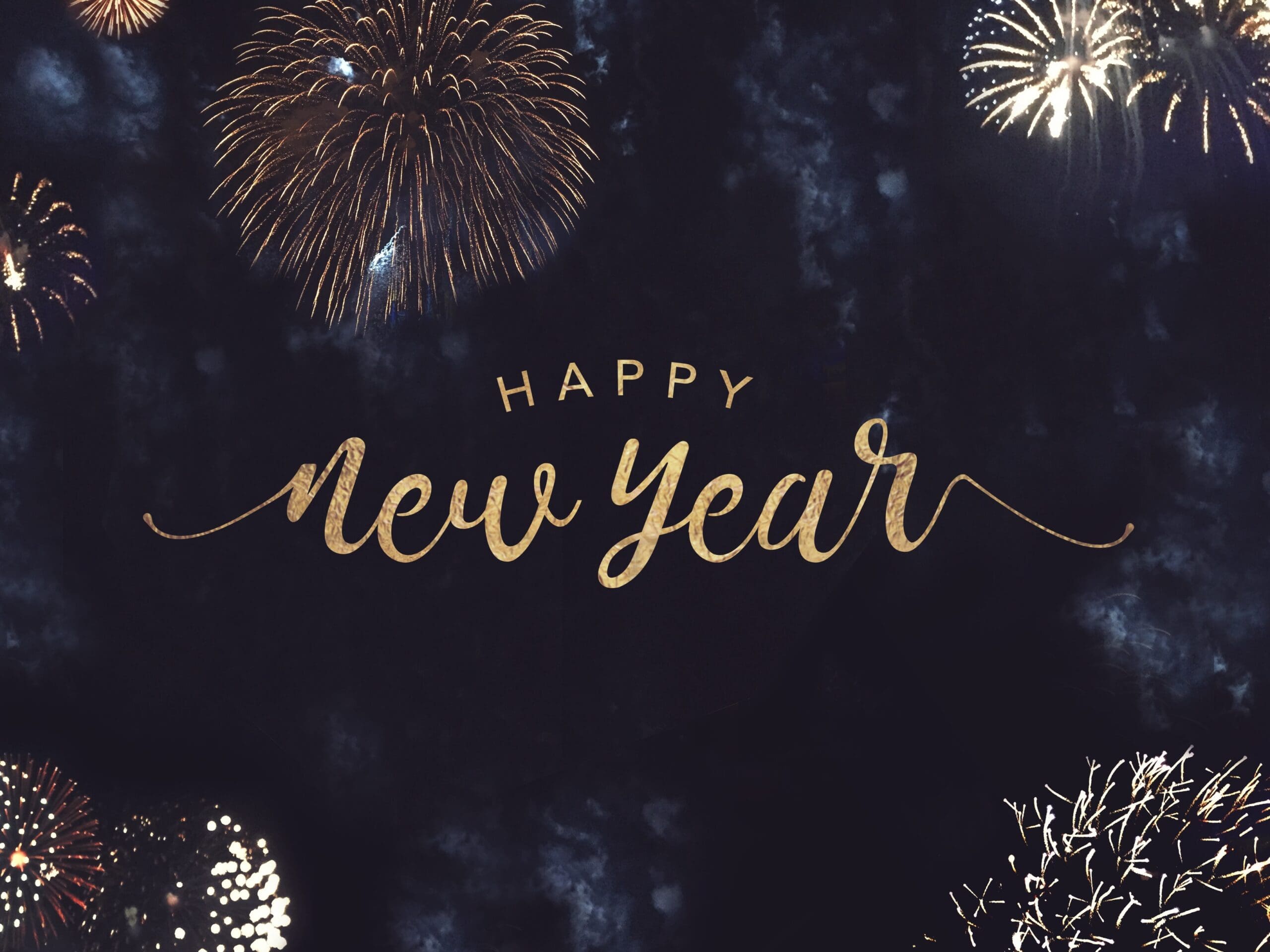 Fireworks in the night sky with "Happy New Year" in gold script in the center.