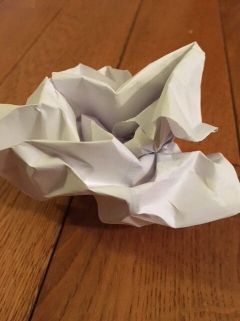 Crumpled piece of white paper on wooden surface