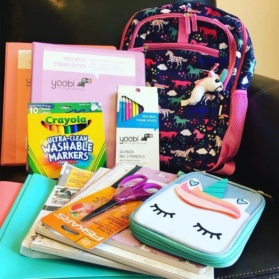 School supplies including notebooks, pens, and a unicorn-themed pencil case, with a backpack featuring colorful animals.