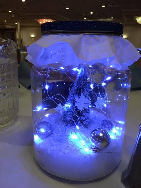 Jar with blue lights, snowflake decoration, and ornaments inside.
