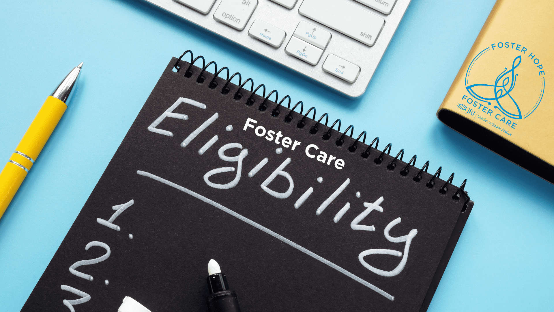 Notebook with 'Foster Care' and 'Eligibility' written on it, with a white keyboard and a yellow pen nearby.