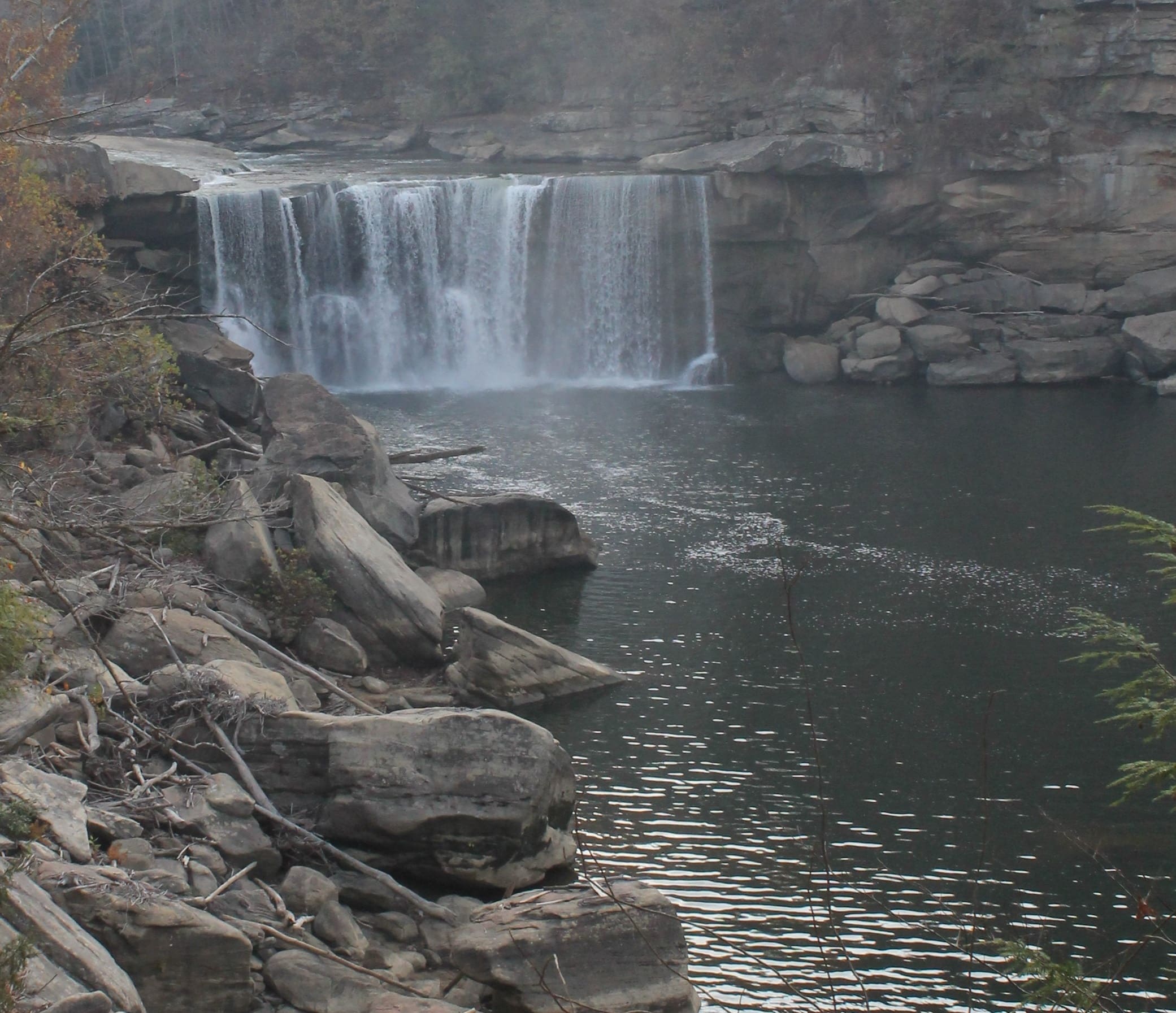 Waterfall over rocks with trees in the foreground