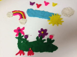 Colorful handmade craft with a rainbow, sun, clouds, and flowers.